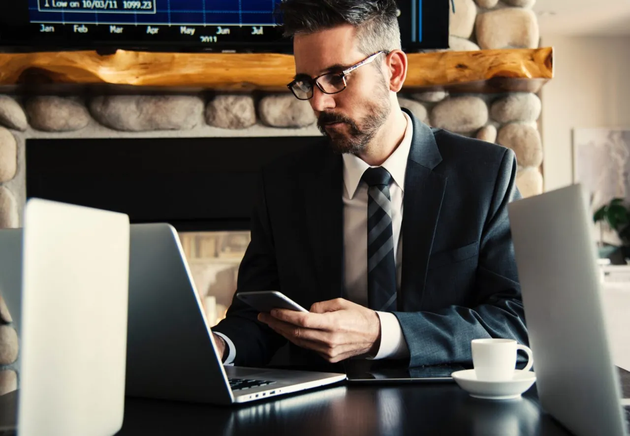 Man in a suit sitting at a desk, using his laptop.